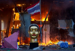 A statue of Buddha and a torn Thai national flag remain in front of Bangkok's Central World shopping mall, as it burns